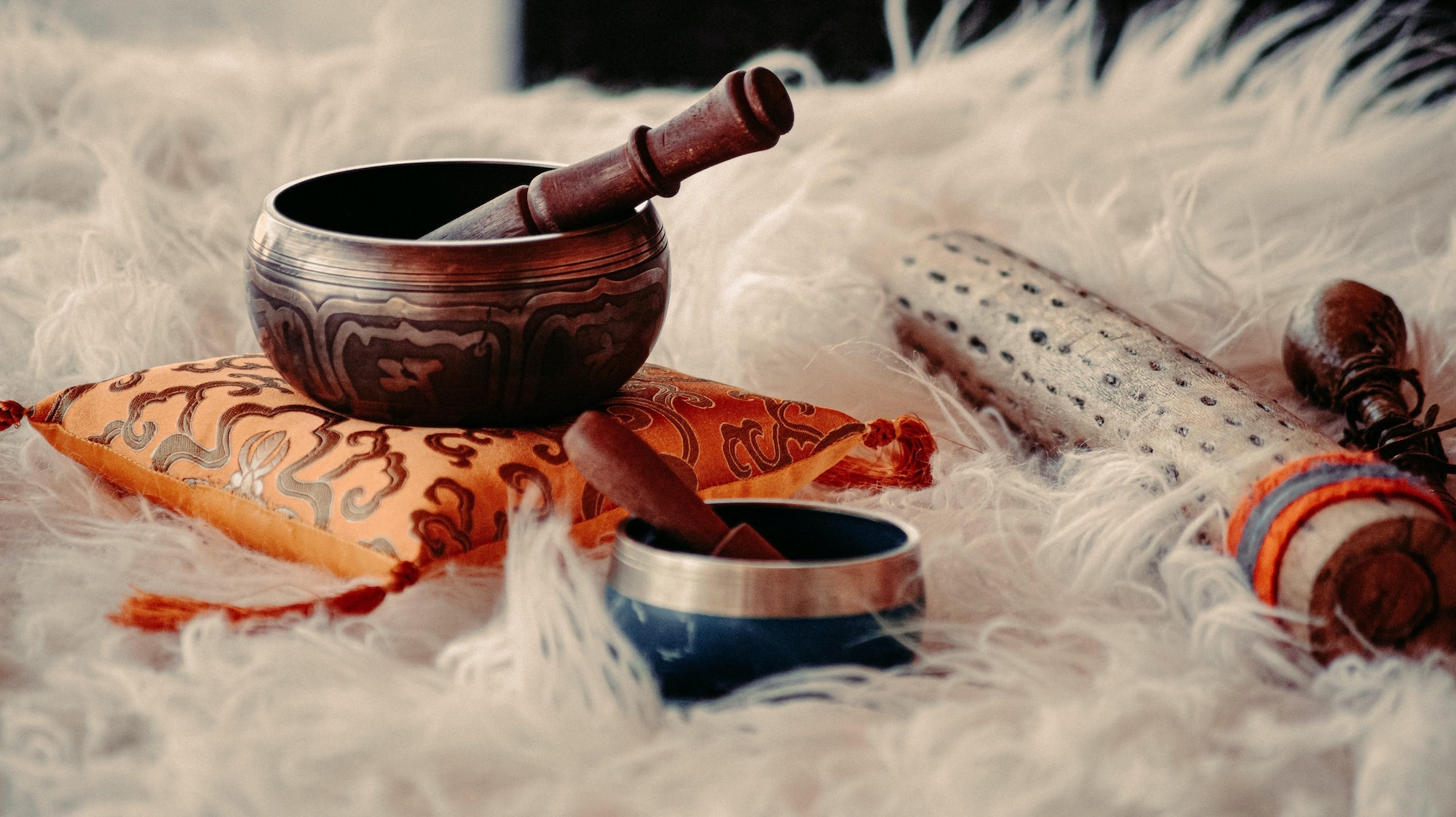 Closeup of Tibetan singing bowls and other Shamanic tools for energy healing on a fluffy surface